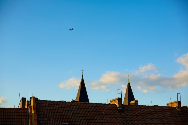 A passenger plane flies over the cones of the rooftops in the old city