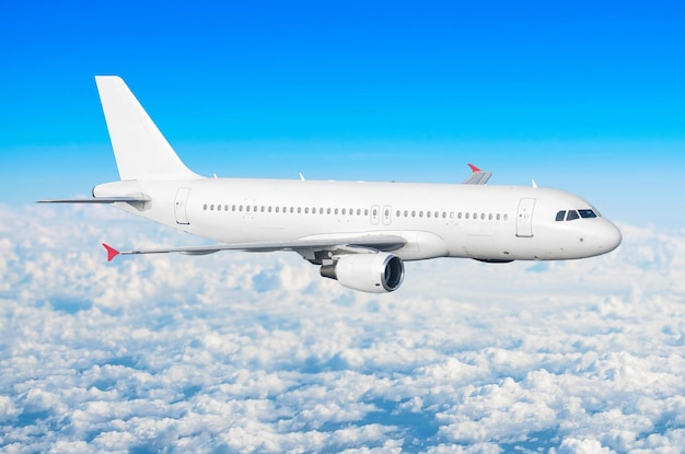 Passenger plane fly on a train above clouds and blue sky.