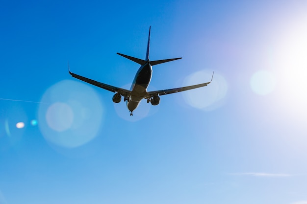 Passenger plane flying in the blue sky in sunlight rays
