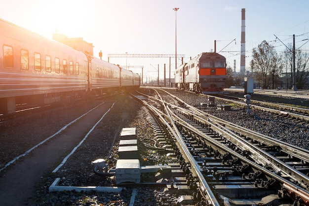Поезд вагонов пассажирского поезда курсирует по железнодорожной станции в прекрасный солнечный день.