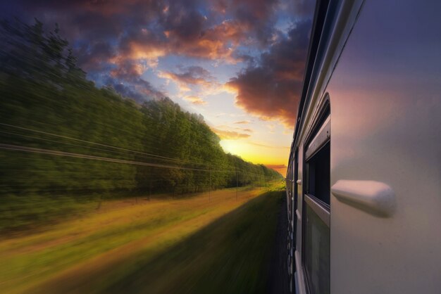 Passenger train in motion with blur effect in the forest at sunset.