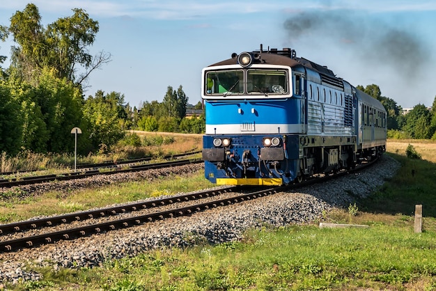 Passenger train rides among fields on a sunny day