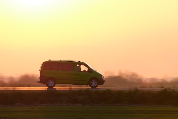 Passenger van driving fast on intercity road at sunset highway\
traffic in evening