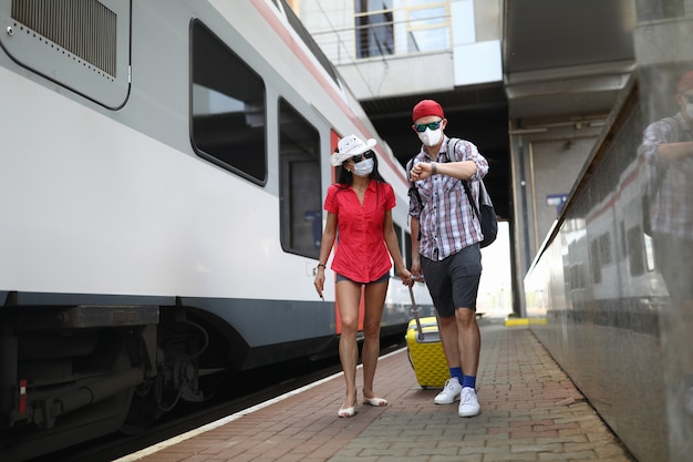 Passengers go with a suitcase to board the train