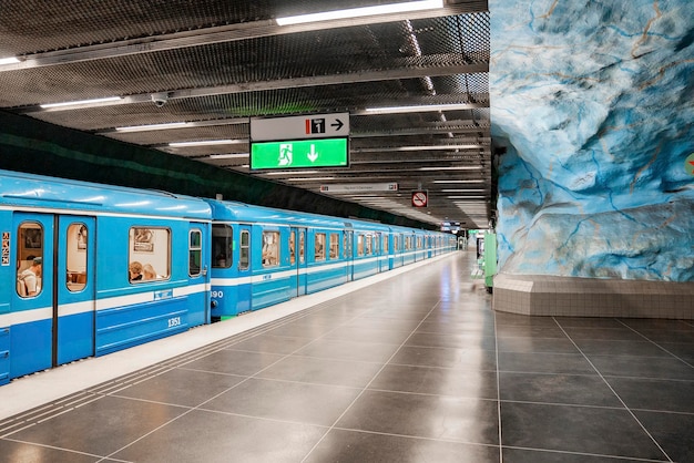 Photo passengers traveling in blue train arrived at illuminated stadion station