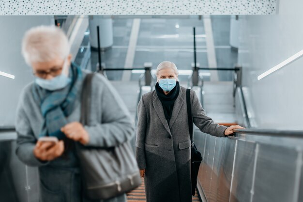 Passengers wearing protective masks keep their distance while standing on the escalator in the subway