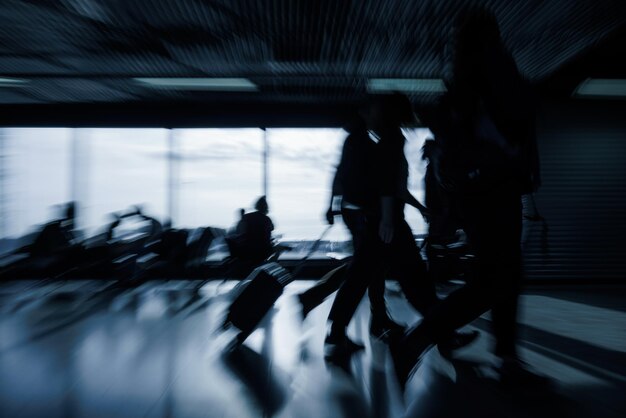 Foto passeggeri con bagagli che camminano lungo una sala di partenza vuota dell'aeroporto