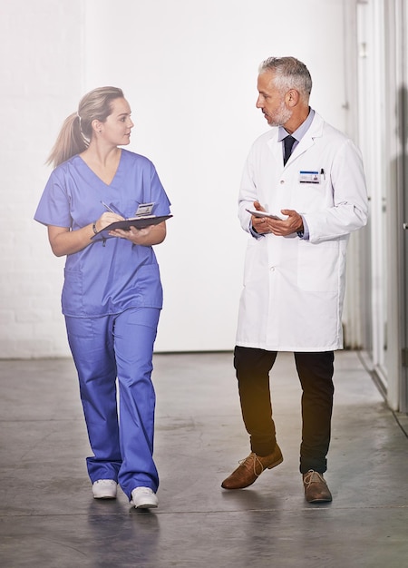 Passing on some of his expertise Full length shot of a mature doctor teaching a female intern in the hospital corridor