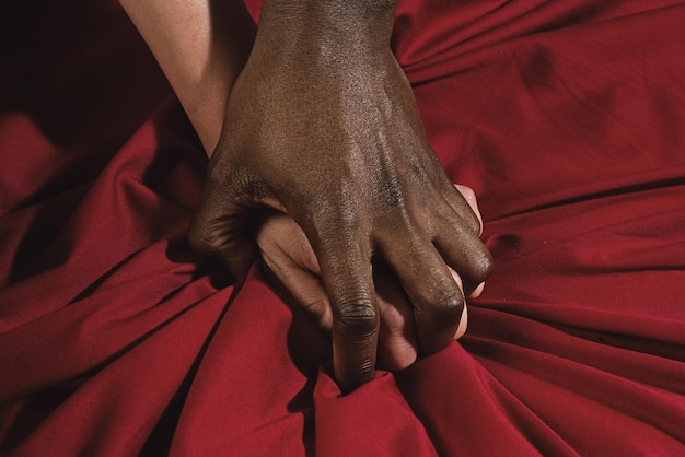 Passion in bed african american and caucasian couple hands pulling white sheets in ecstasy closeup c