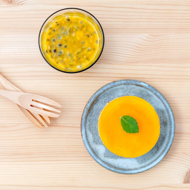 Passion fruit cheesecake with fresh mint leaves on wooden background