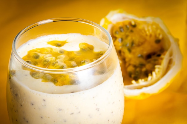 Passion fruit mousse in a glass bowl with passion fruit in the background on a yellow background