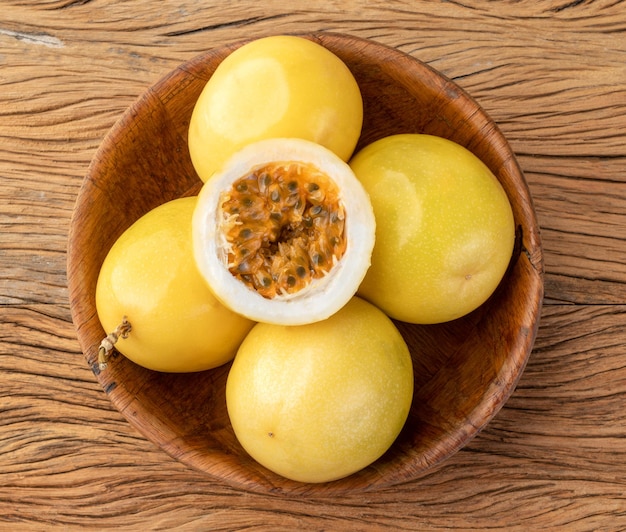 Passion fruits in a bowl with cut fruit over wooden table