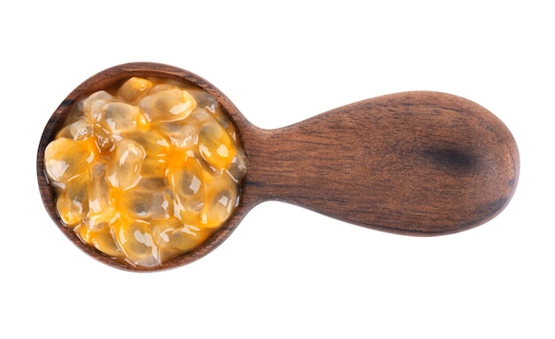 Passion fruits seeds in wooden spoon, isolated on white background. Passionfruit or maracuya pulp, exotic fruit. Top view.