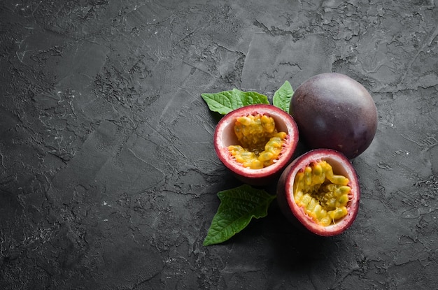 Passion fruits with leaves on a black background Tropical Fruits Top view Free space for text