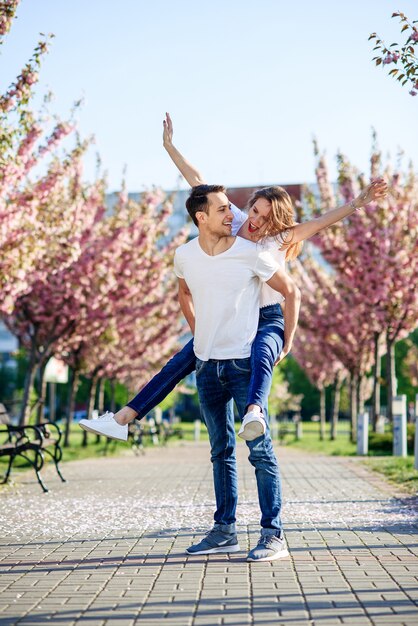 情熱と愛の概念。春の日に咲く庭でキスする男女。