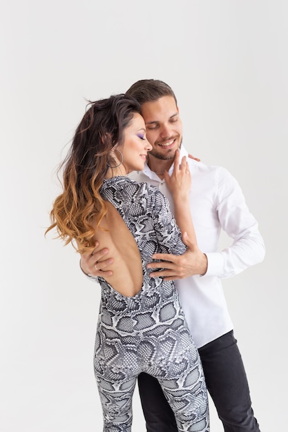 Passionate couple dancing a latin dance on white wall