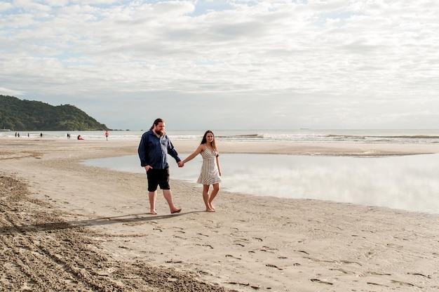 朝のビーチを歩く情熱的なカップル