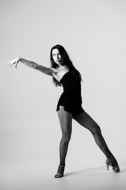 스튜디오에서 열정적인 라티나 댄서가 작은 검은색 드레스를 입고 춤을 추고 있습니다.