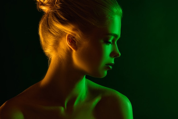 Passioned. Portrait of female fashion model in neon light on dark studio background. Beautiful caucasian woman with trendy make-up and well-kept skin. Vivid style, beauty concept. Close up. Copyspace