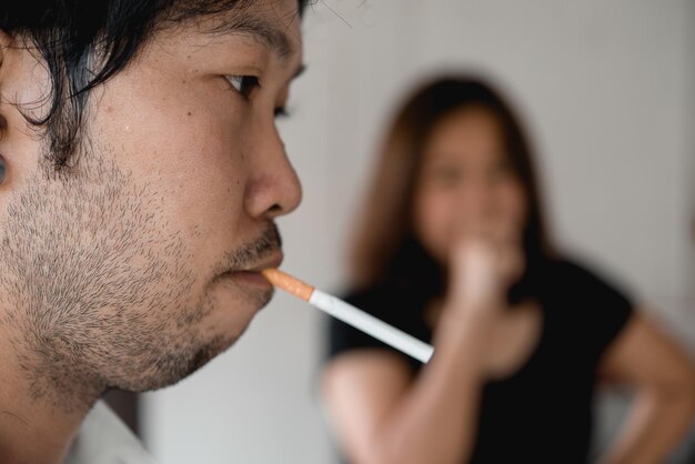 受動喫煙の概念アジア人男性はタバコを吸っており、女性は顔を覆っているタバコの日はありません喫煙は社会に不快です