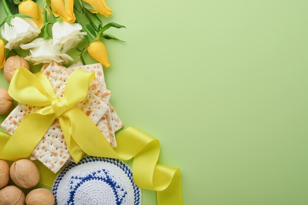 Passover celebration concept matzah kosher red wine walnut and spring white and yellow rose flowers traditional ritual jewish bread on light green background passover food pesach jewish holiday