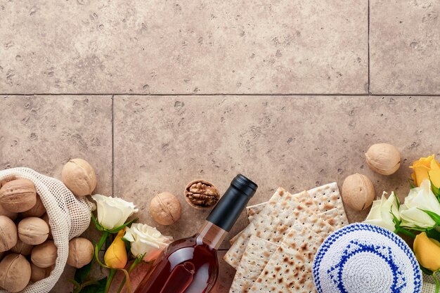 Photo passover celebration concept matzah kosher red wine walnut and white and yellow roses traditional ritual jewish bread on sand color old tile wall background passover food pesach jewish holiday