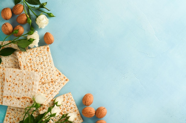 Концепция празднования Пасхи Маца красный кошерный орех и весенние красивые цветы розы Традиционный ритуальный еврейский хлеб на светло-бирюзовом или синем фоне Пасхальная еда Песах Еврейский праздник