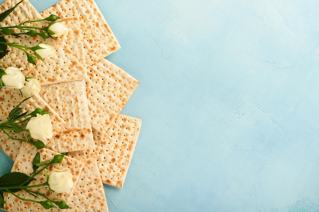 Passover celebration concept Matzah red kosher walnut and spring beautiful rose flowers Traditional ritual Jewish bread on light turquoise or blue background Passover food Pesach Jewish holiday