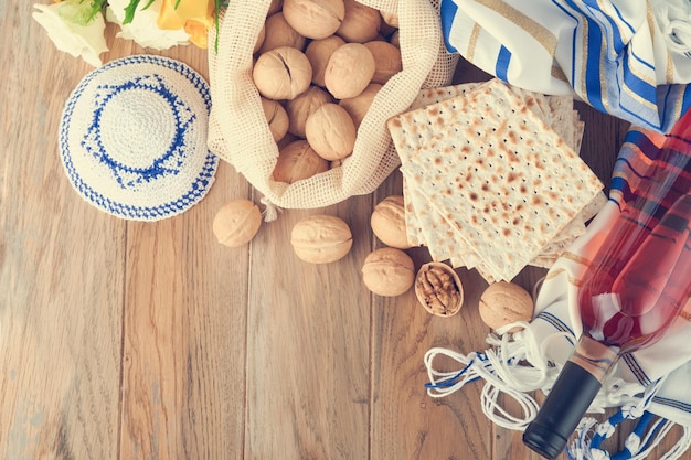 Passover celebration concept Matzah red kosher and walnut Traditional ritual Jewish bread matzah kippah and tallit on old wooden background Passover food Pesach Jewish holiday Toned image