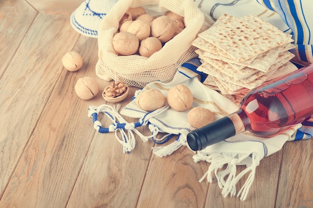 Passover celebration concept Matzah red kosher and walnut Traditional ritual Jewish bread matzah kippah and tallit on old wooden background Passover food Pesach Jewish holiday Toned image