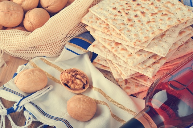 Passover celebration concept Matzah red kosher and walnut Traditional ritual Jewish bread matzah kippah and tallit on old wooden background Passover food Pesach Jewish holiday Toned image