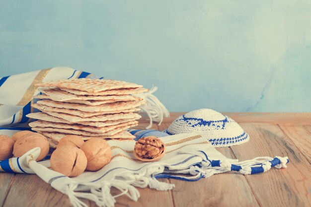 Passover celebration concept Matzah red kosher and walnut Traditional ritual Jewish bread matzah kippah and tallit on old wooden background Passover food Pesach Jewish holiday Toned image