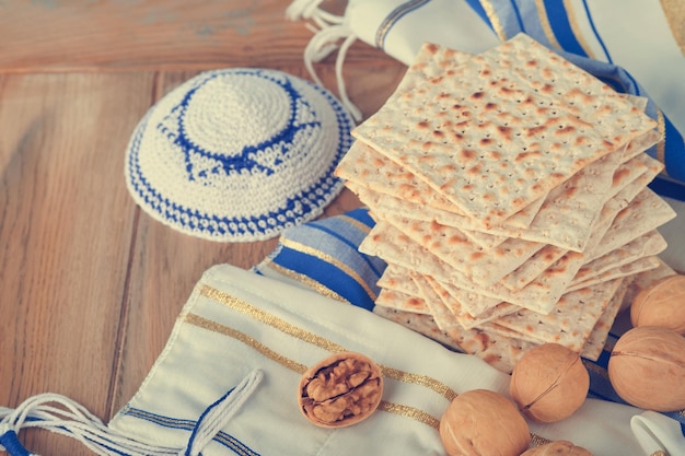 Passover celebration concept Matzah red kosher and walnut Traditional ritual Jewish bread matzah kippah and tallit on old wooden background Passover food Pesach Jewish holiday Toned image