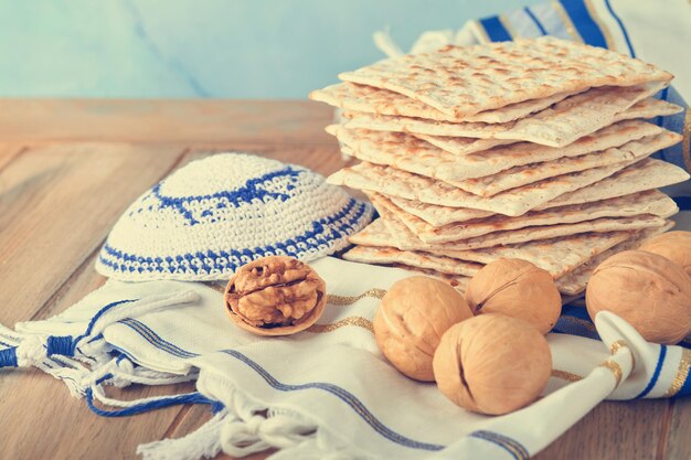 Passover celebration concept Matzah red kosher and walnut Traditional ritual Jewish bread matzah kippah and tallit on old wooden background Passover food Pesach Jewish holiday Toned image