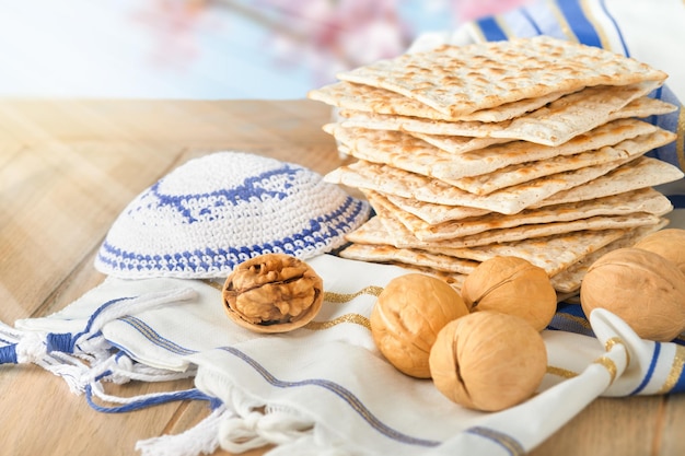 Passover celebration concept Matzah red kosher and walnut on wooden vintage table table in front of spring blossom tree garden and flowers landscape with sun rays with copy space Mock up