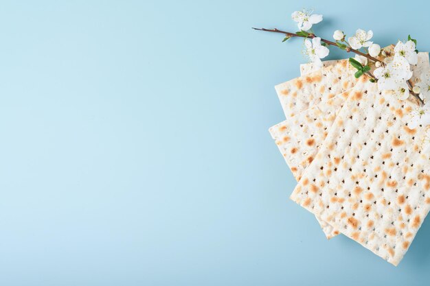 Passover celebration concept Matzah red kosher wine walnut and spring beautiful branch of full bloom cherry or apple Traditional Jewish bread on light blue background Pesach Jewish holiday