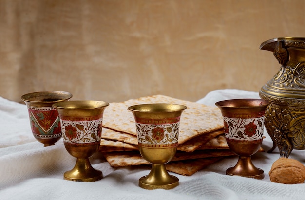 Passover matzoh jewish holiday bread, four glasses kosher wine over wooden table.