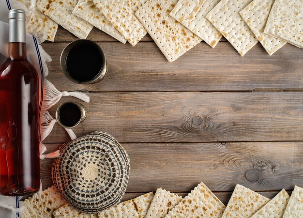 木製のテーブルの背景の上に過越祭マッツォユダヤ教の祝日パンとコシェルワイン。コピースペース。フラットレイ。
