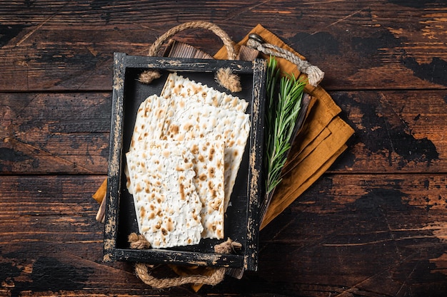 Passover matzos of celebration with matzo unleavened bread in a wooden tray with herbs Wooden background Top view