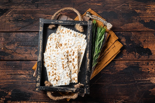 Foto matzos pasquali di celebrazione con pane azzimo matzo in un vassoio di legno con erbe sfondo in legno vista dall'alto