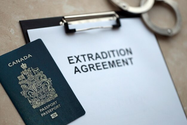 Passport of canada and extradition agreement with handcuffs on table close up