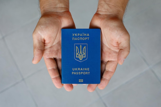 Passport of a citizen of Ukraine in a male hand on a gray background closeup