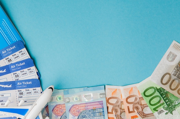 Passport, dollars and euro, plane and air ticket on a blue background. Travel concept, copy space