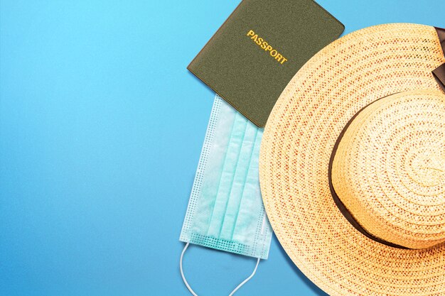 Passport and hat with a face mask on a colored surface. Traveling in the new normal