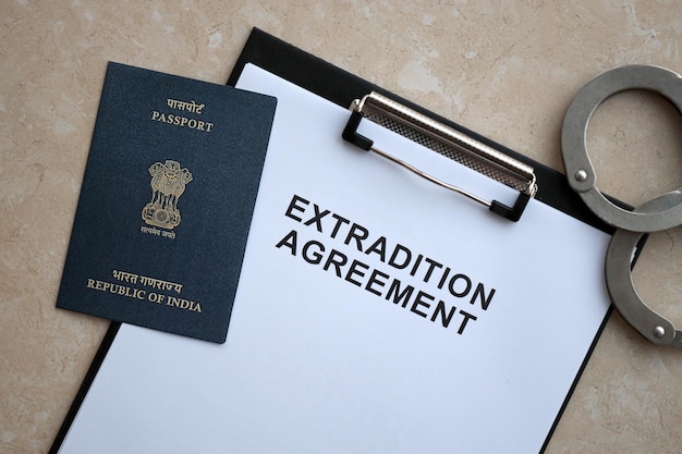 Photo passport of india and extradition agreement with handcuffs on table close up