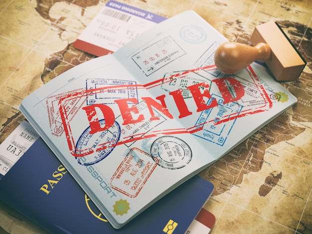 Passport with denied visa stamp on the map of the world and airline boarding pass ticketsTravel concept