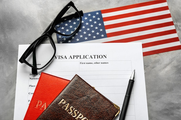 Passports, American flag and visa application form on table. Immigration to USA