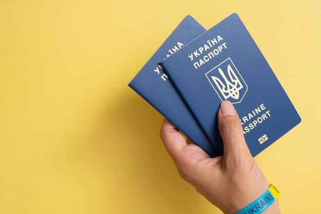 Passports of a citizen of Ukraine in a female hand on a yellow background closeup Inscription in Ukrainian Ukraine Passport