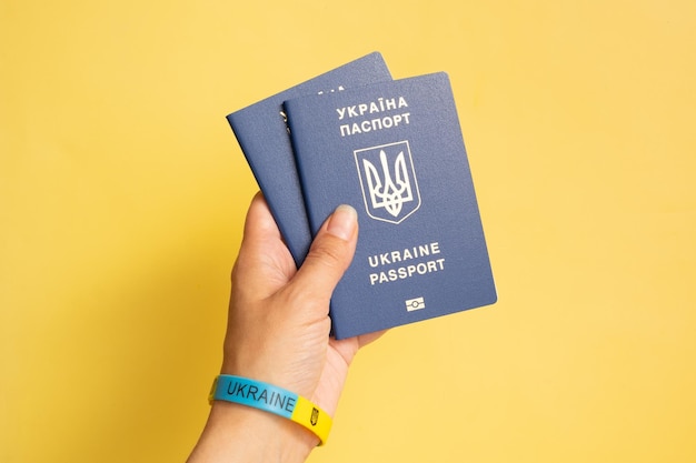 Passports of a citizen of Ukraine in a female hand on a yellow background closeup Inscription in Ukrainian Ukraine Passport