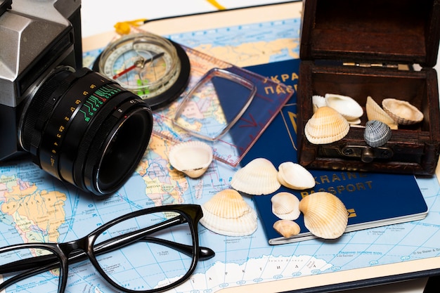 Foto passaporti su una mappa del mondo. macchina fotografica, occhiali da sole e conchiglie sullo sfondo